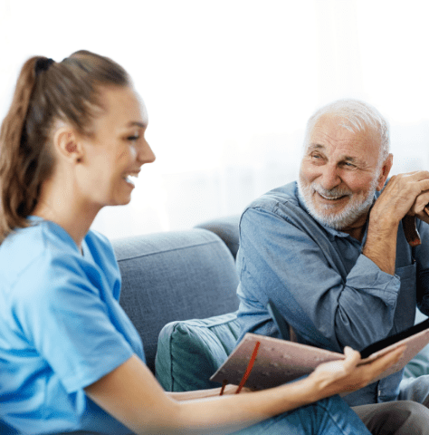 Nurse and male client smiling as she shows him a photo album