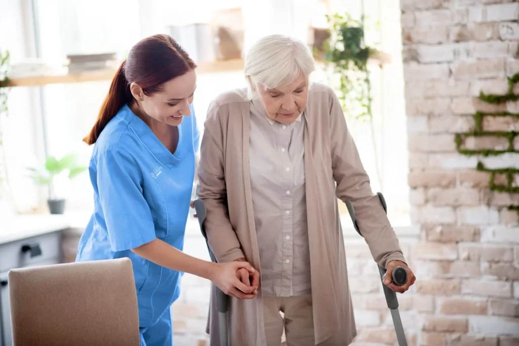 Caregiver assisting someone with walking, offering support and guidance during the activity.